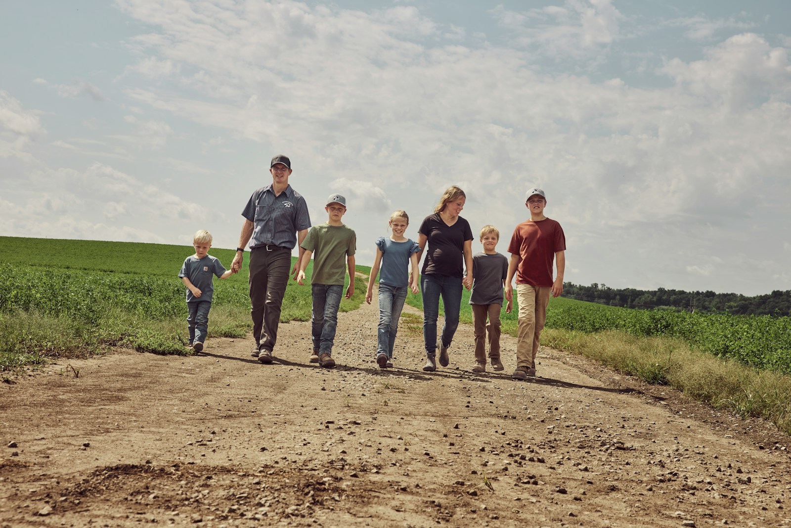 Familia agrícola de distintas edades caminando junta en el campo